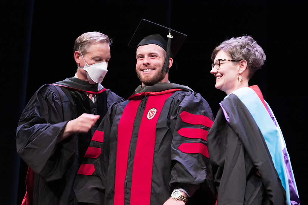 Class of 2022 PharmD graduate Casey Davis receives his hood from Professor John Dopp and Advisor Rebecca Beebe