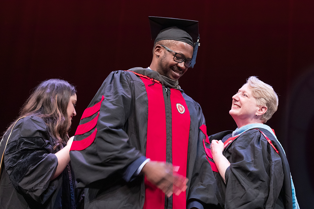 Class of 2022 PharmD graduate Newton Koo receives his hood from professors Marina Maes and Karen Kopacek