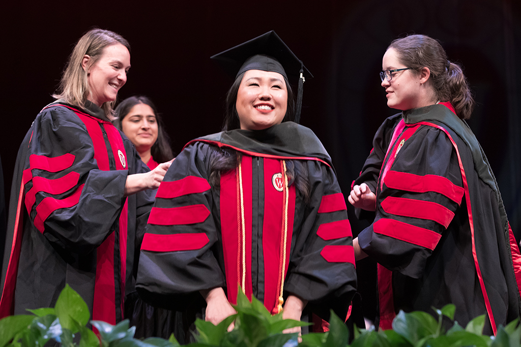 Class of 2022 PharmD graduate Tracy Lor receives her hood from professors Kate Rotzenburg and Amanda Margolis