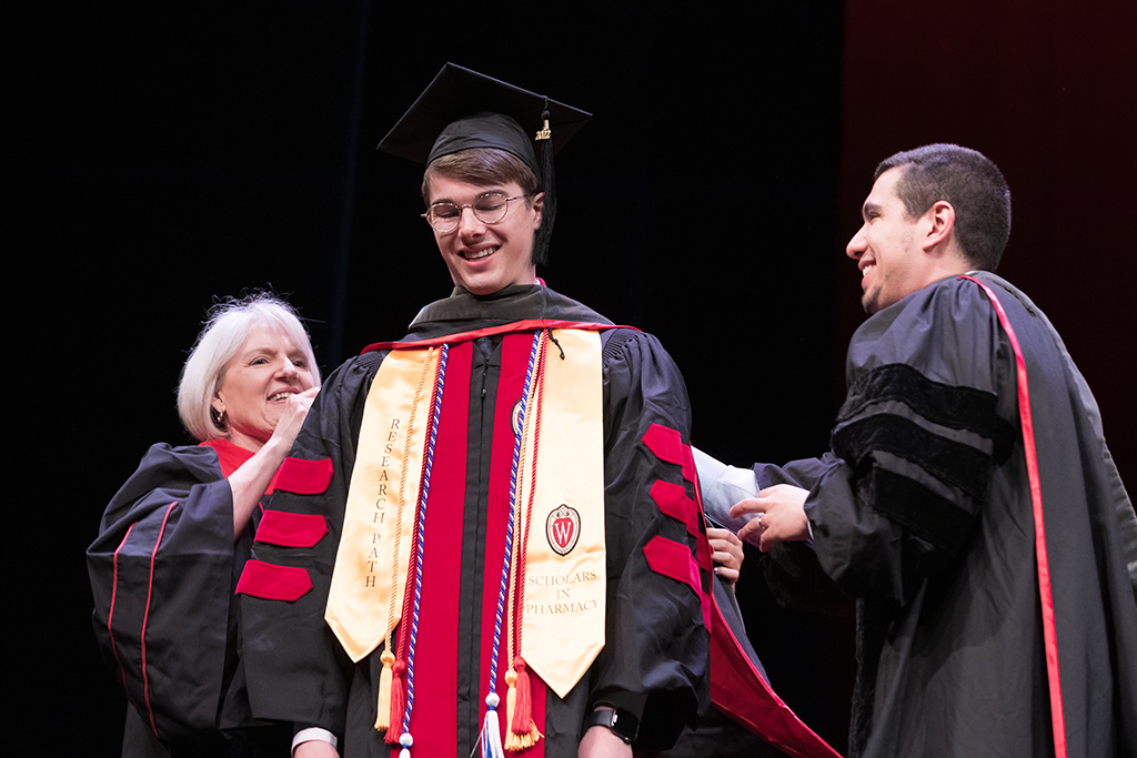 Class of 2022 PharmD graduate Alex Peterson-Weber receives his hood from Professors Bonnie Fingerhut and Ed Portillo