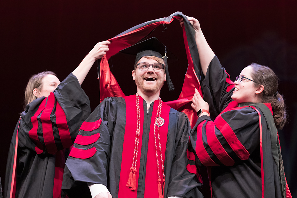 Class of 2022 PharmD graduate Jacob Richie receives his hood from professors Kate Rotzenburg and Amanda Margolis