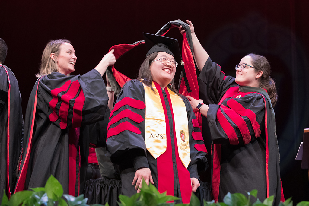 Class of 2022 PharmD graduate Mary Vang receives her hood from professors Kate Rotzenburg and Amanda Margolis