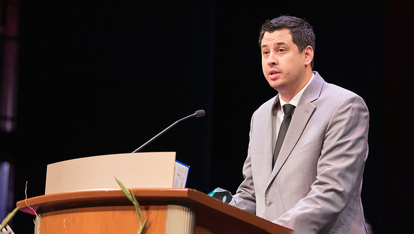 Josh Lee speaking at a podium during the 2022 Hooding Ceremony