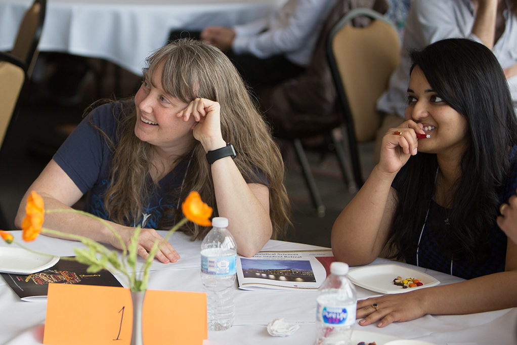 Students, alumni, and faculty sitting around tables during trivia at the PharmSci retreat