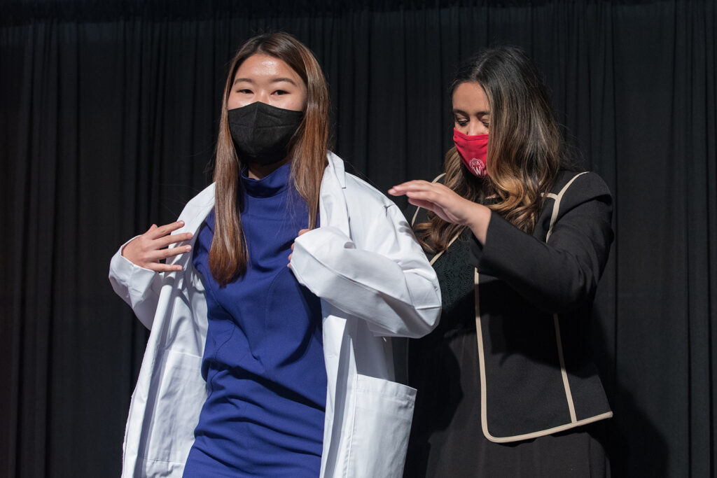 Student wearing their white coat on-stage