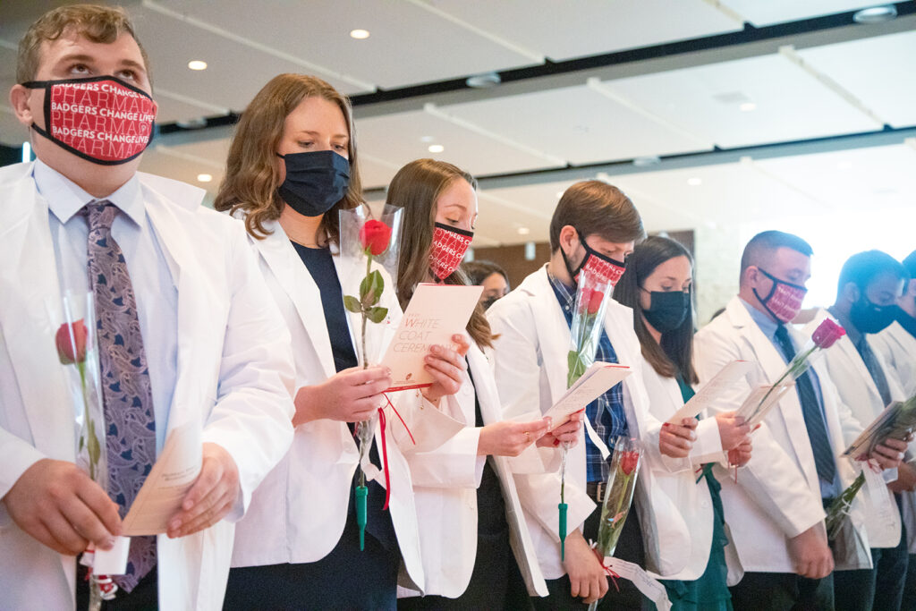 Pharm students holding roses and white coat ceremony pamphlets