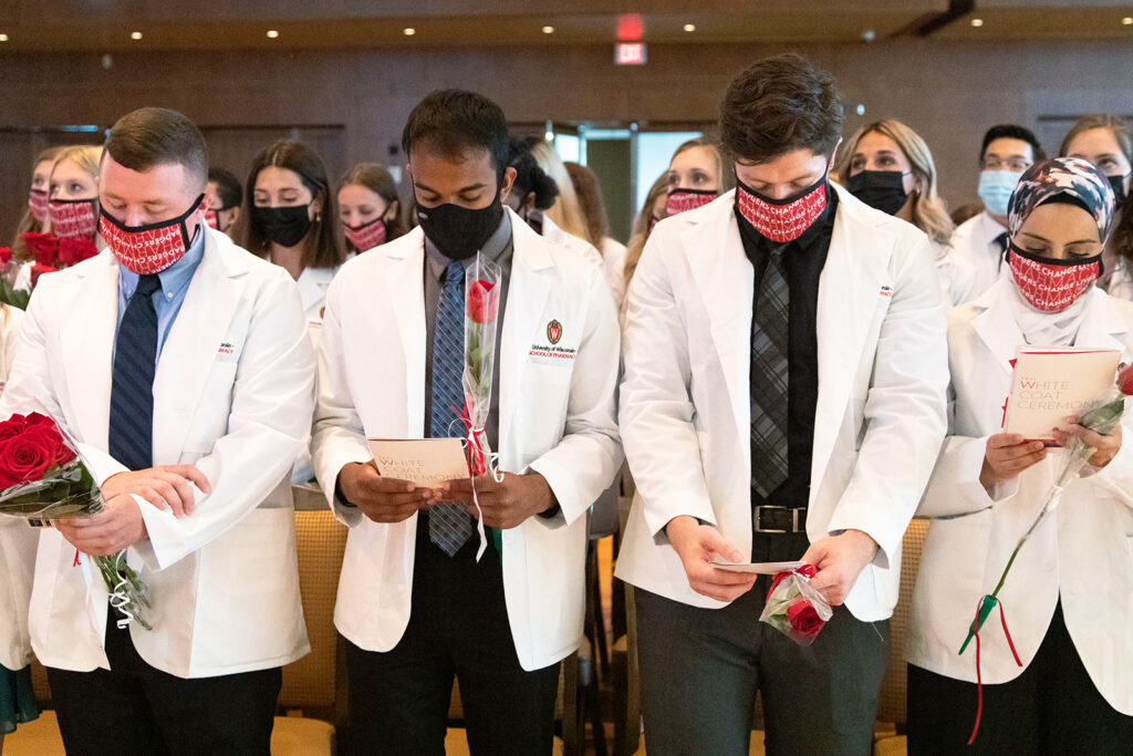 Pharm students holding roses and white coat ceremony pamphlets