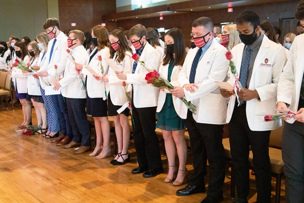 Pharm students holding roses and white coat ceremony pamphlets