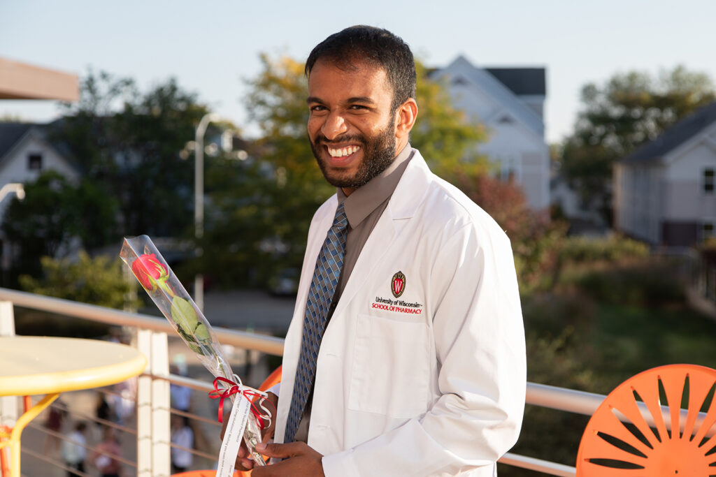 Pharm student holding a rose and wearing their white coat after white coat ceremony