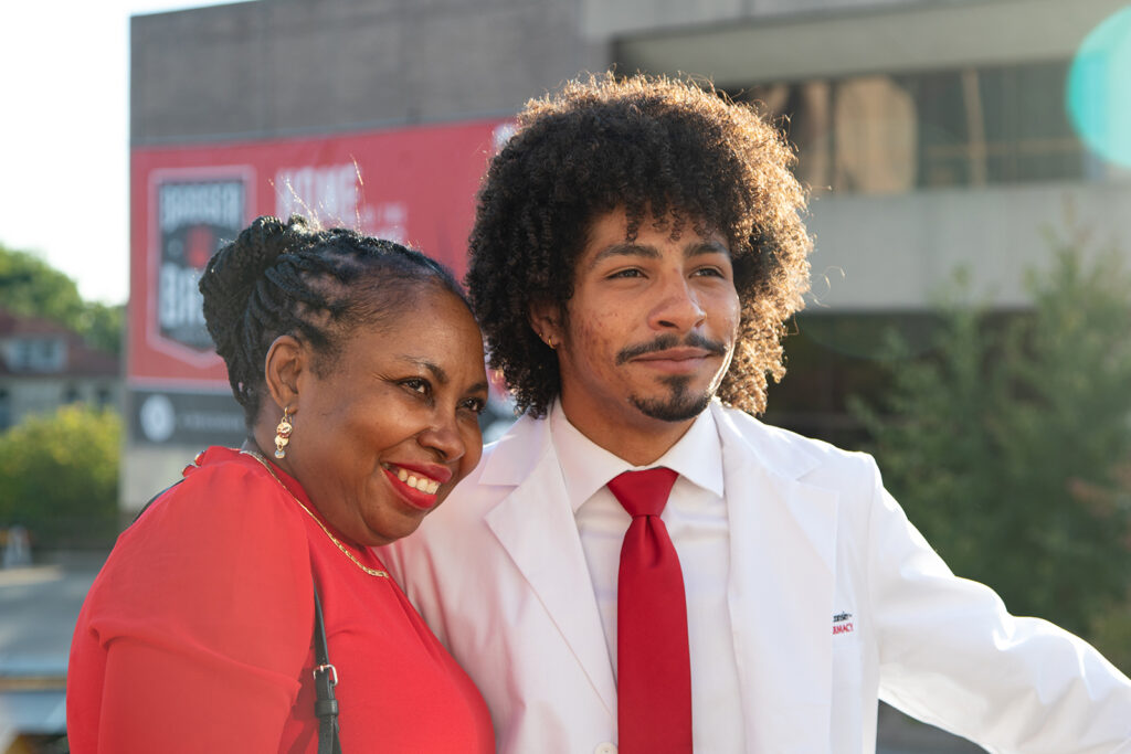 Pharm student wearing white coat and taking a picture with their mother after white coat ceremony