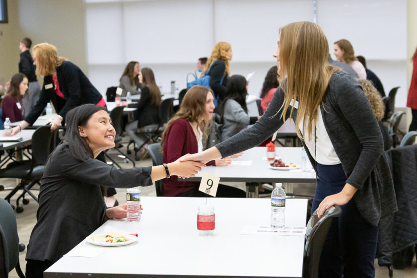 Two women shaking hands over a table