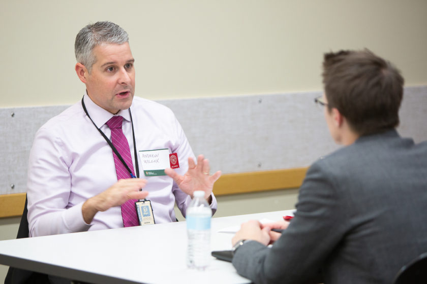 Andrew Wilcox speaking to man wearing suit