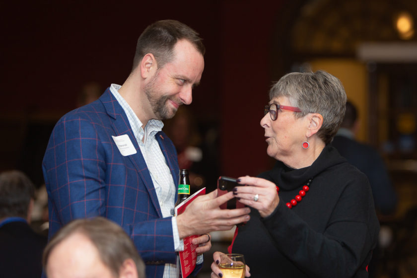 Man helping older woman with her phone at citations of merit dinner