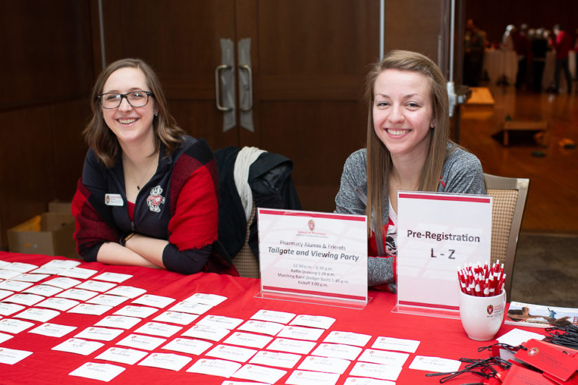 Girls behind sitting check-in table for Alumni Tailgate and Viewing Party