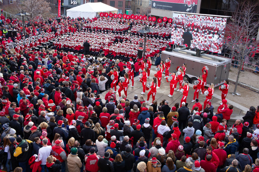 Alumni Tailgate and Viewing party with large outdoor crowd and marching band with cheerleaders