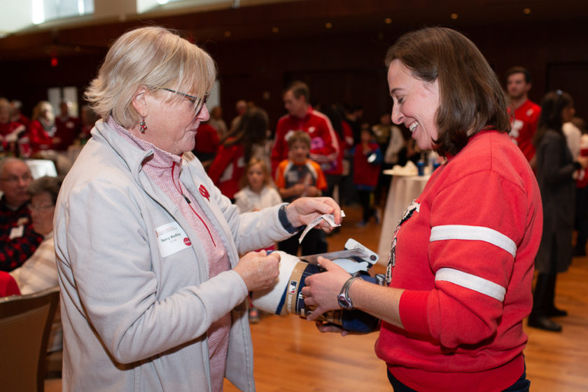 Woman giving ticket to staff for blanket she won at Alumni Tailgate & Viewing Party