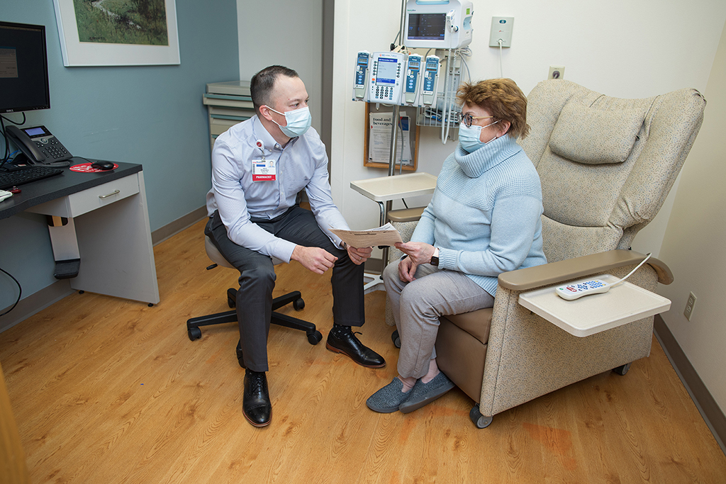 Jason Bergsbaken speaks with a woman in a sweater in a clinic room