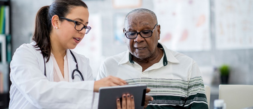 A pharmacist shares medication dosage information with a patient on a tablet during an appointment