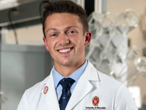 PharmD student Connor poses in his white coat