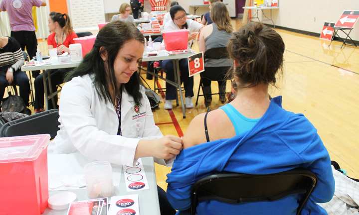 Third-year PharmD student Brianna Jacques applies an adhesive bandage to the arm of a vaccine recipient.