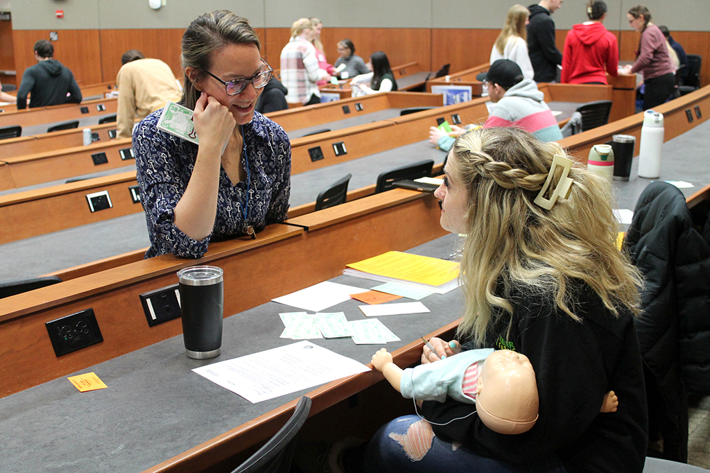 Associate Teaching Professor Kate Rotzenberg (PharmD ’07) works with a PharmD student during the poverty simulation.