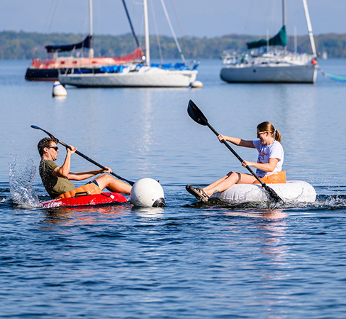Graduate students Liam Dixon (left) and Emilee Gaulke (right) race pumpkins around a buoy on Lake Mendota.