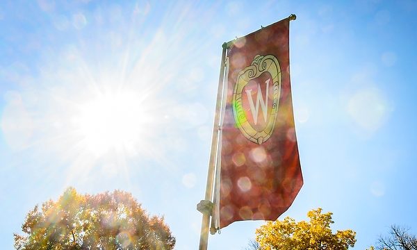 Sunlight shines through an iconic W crest banner on Bascom Hill at UW-Madison.