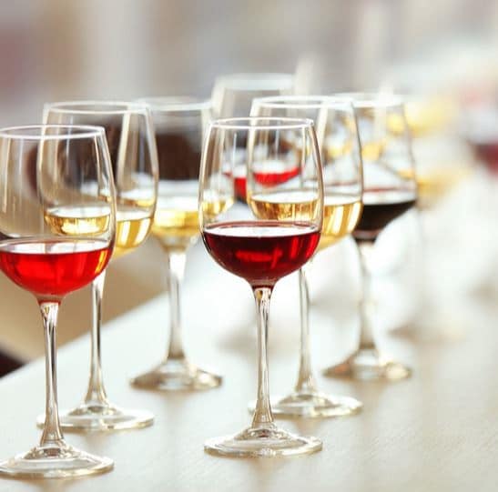 A row of glasses with colorful wines lines an elegant table